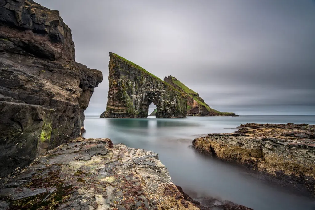 An image of the iconic sea stacks Drangarnir in the Faroe Islands, with stormy weather in the background.
